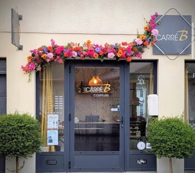 Façade extérieure accueillante du salon Carré B avec arche fleurie