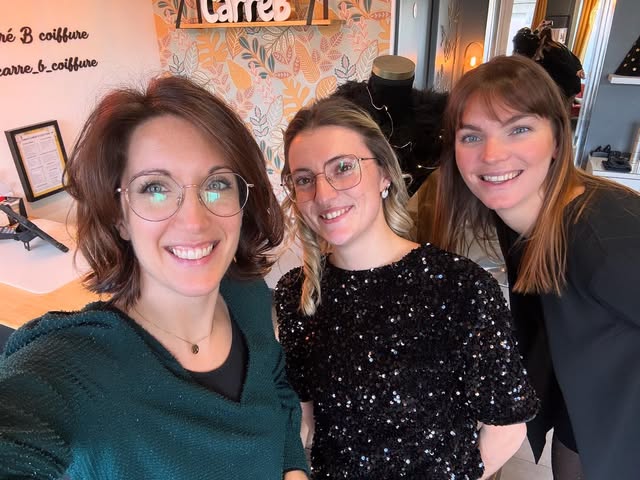 Trois coiffeuses souriantes de l'équipe Carré B coiffure posant ensemble dans leur salon.